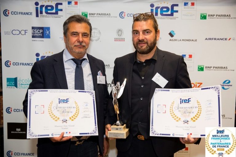 Deux hommes tenant des trophées et des certificats lors d'un événement.